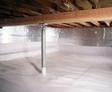 Crawl space with exposed wooden beams and metal support posts, featuring reflective insulation on walls.