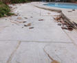 Weathered stone pathway with scattered leaves next to a tranquil outdoor pool.