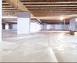A well-lit crawl space with a dehumidifier, plastic vapor barrier, and wooden beams above.