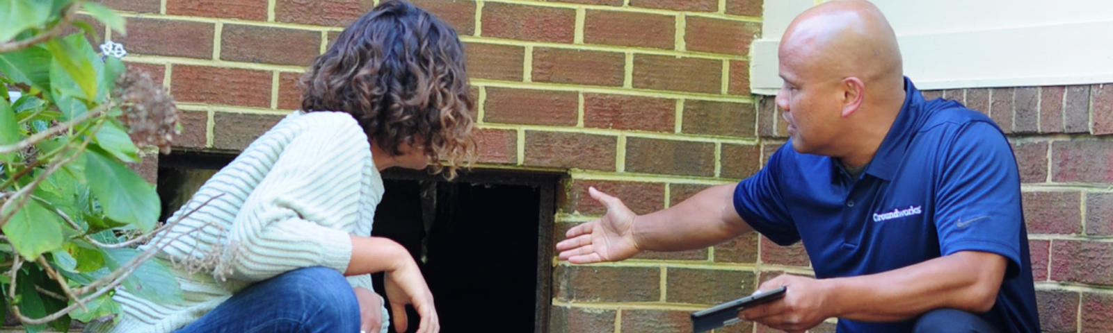 CFI speaking to homeowner while pointing at crawl space door opening.