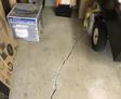 Cracked garage floor with boxes and a dolly on the side.