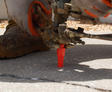 Close-up of a worker injecting material into a concrete crack using specialized equipment.