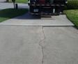 Cracked concrete driveway with a truck parked partially on it.