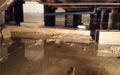 Flooded crawl space with standing water and concrete pillars.