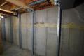 Basement wall with steel support beams and visible cracks along the concrete surface.