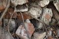 Close-up of weathered bricks and stones intertwined with roots and dry leaves.