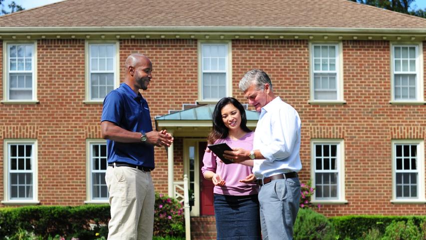 CFI standing with homeowners outside of home.
