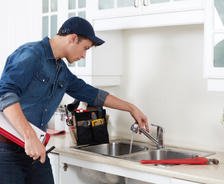 Plumber repairing kitchen sink garbage disposal.