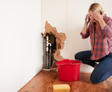 Women with burst pipe showing through wall while on the phone