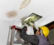 Technician repairing the pipe in the water-damaged ceiling.