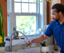 A1 technician checking water in kitchen sink.