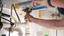 Hands tightening pipes under the sink with a wrench.