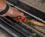 Hands holding gas line valve.