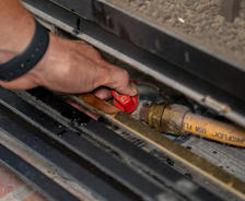 Hands holding gas line valve.