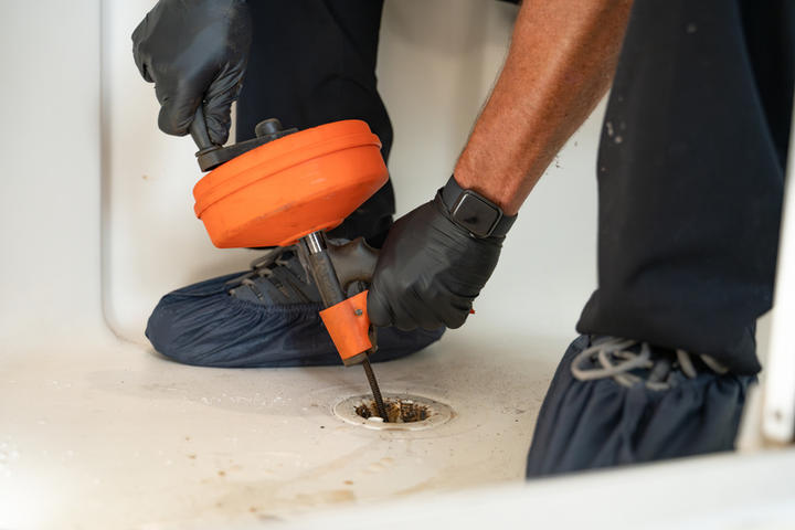 Technician snaking the drain of a bathtub.
