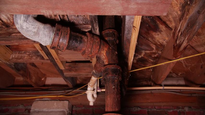 Rusty pipes and rotten wood in the crawlspace.