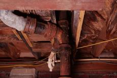 Rusty pipes and rotten wood in the crawlspace.