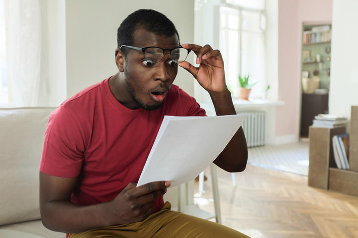 Man checking a bill with surprised facial expression.