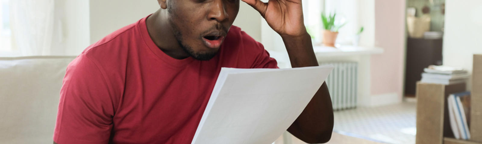 Man checking a bill with surprised facial expression.