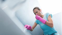 Woman with pink gloves on plugging nose due to bad smell.