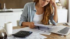 Frustrated woman going over bills at kitchen table.
