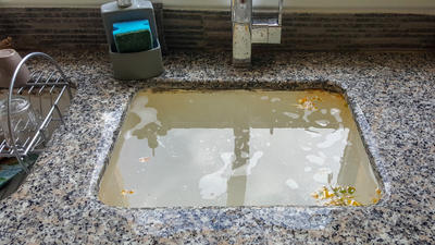 Clogged sink filled with dirty water caused by drain clog.