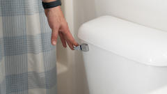Man pressing toilet lever to flush toilet.