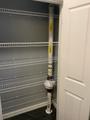 Empty wire shelves in a closet with a radon mitigation system installed on one side.