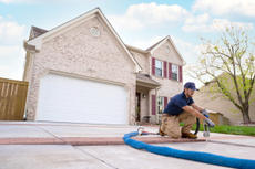 Production crew installing polyrenewal concrete lifting in front of brick house