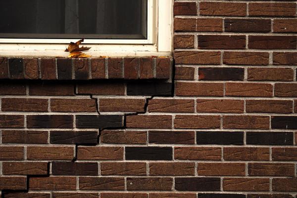 Cracked exterior brick wall under window.