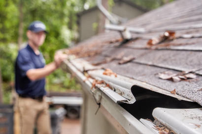 Groundworks technician inspecting clogged gutters