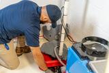 service tech working on a sump pump in the basement and explaining how a sump pump can help when it floods in the area