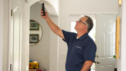 A man in a blue polo shirt is using a device to inspect a home