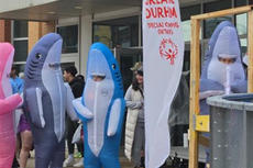 People in inflatable shark costumes stand near a "Greater Durham Special Olympics Ontario" flag.