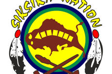 Siksika Nation logo with a buffalo, feathers, and two crossed tools on a yellow and green circle.