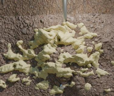 White liquid expanding foam fills gaps and cracks in a rough, porous concrete surface.