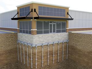 A building with its foundation supported by many vertical steel piers anchored deep into the ground.