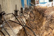 Exposed foundation with steel piers and cables during building repair or stabilization work.