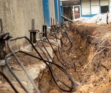 Exposed foundation with steel piers and cables during building repair or stabilization work.