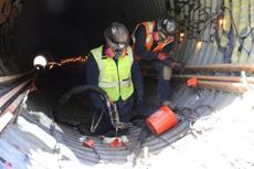 Two construction workers in safety gear work inside a tunnel, using tools near rebar and concrete. Culvert Rehabilitation with Polyurethane