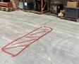 Red spray-painted rectangle with diagonal lines on a warehouse floor near pallets and boxes.