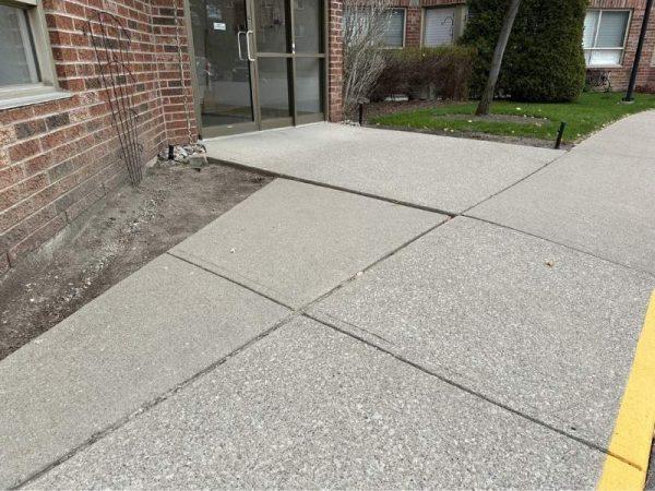 A sidewalk ramp leads to a building entrance, but it is blocked by a raised curb.