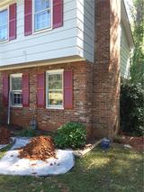 Brick house with red shutters and garden work in progress, including soil piles and tarp.