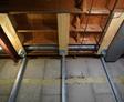 Exposed ceiling with wooden beams, metal ducts, and visible insulation in a construction site showcasing advanced foundation repair solutions.