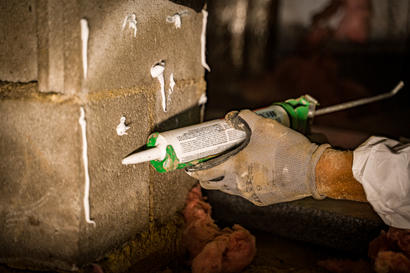caulk gun with epoxy sealant on block basement wall