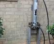 A hydraulic jack system is set up next to a brick house wall for foundation repair.