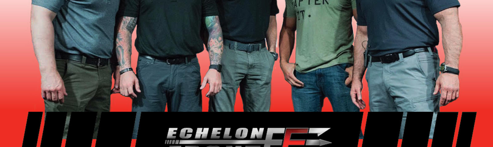 Five men standing together in front of a white background with logos, wearing black and gray shirts.