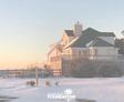 A large house with a snowy yard at sunset, featuring a wooden deck and a logo in the bottom corner.
