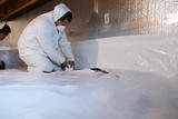 Crew installing a vapor barrier in crawlspace.