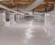 A clean, sealed crawl space with white vapor barrier sheets and ductwork visible overhead.